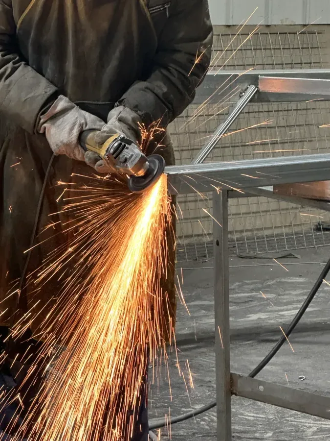 Factory worker grinding a padel court steel frame